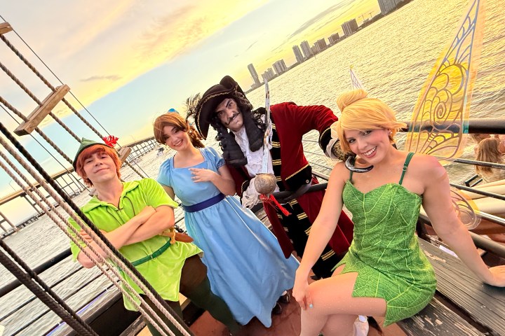Four people in Peter Pan costumes on a ship deck at sunset.