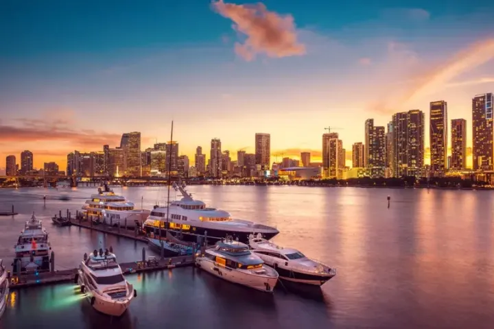 City skyline at sunset with boats docked in the foreground.