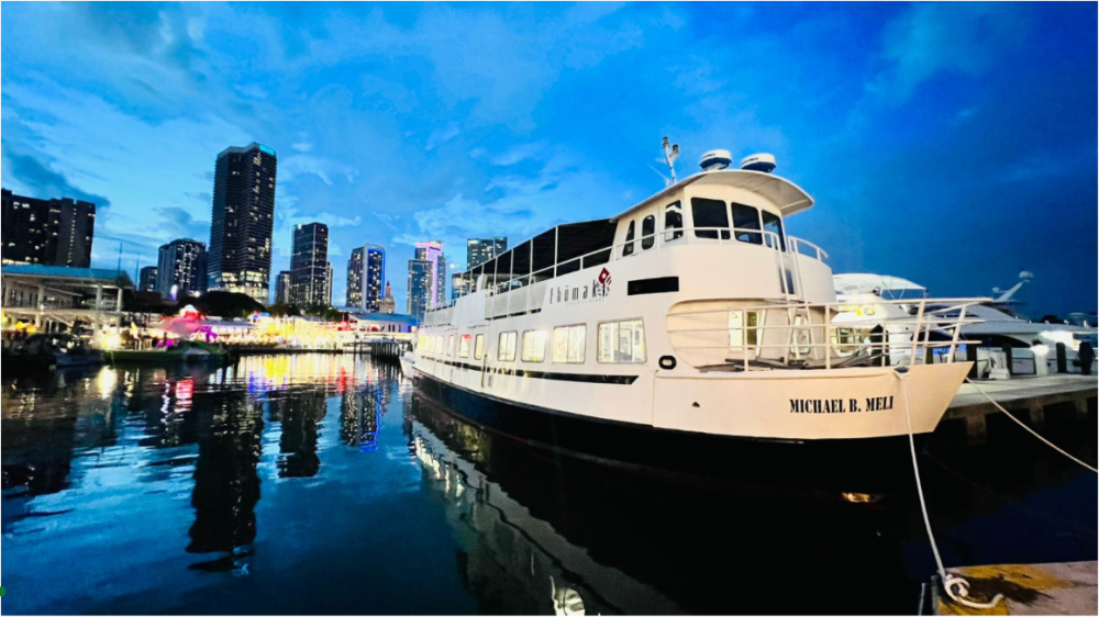 White boat docked in a harbor with city skyline at dusk.