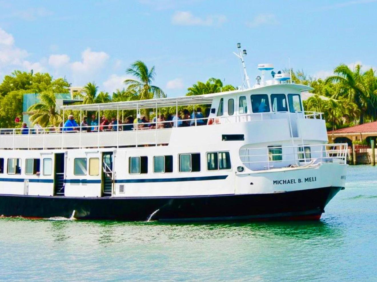 A white passenger ferry on a sunny day with palm trees in the background.