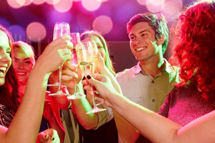 Group of people smiling, toasting with champagne glasses at a party.