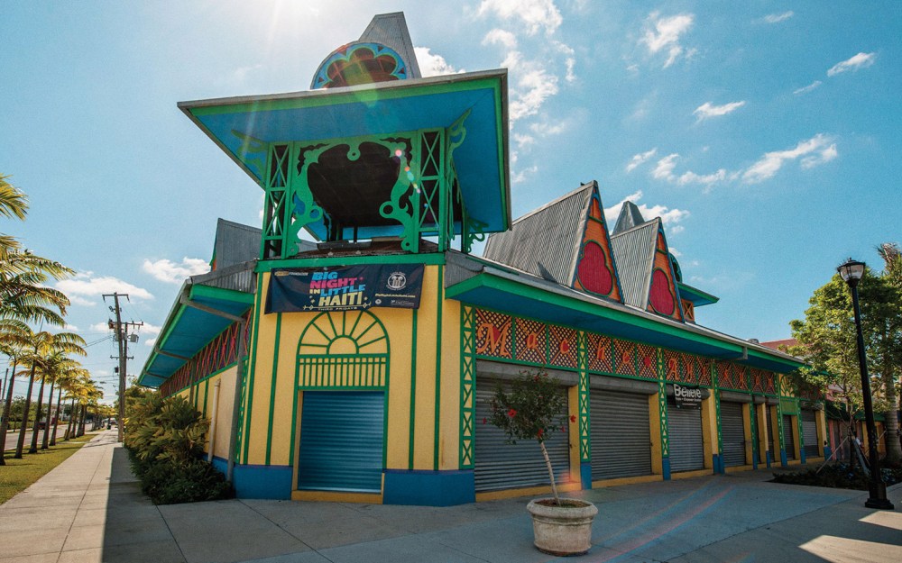 Colorful building with geometric designs, palm trees, and a banner under a bright sky.
