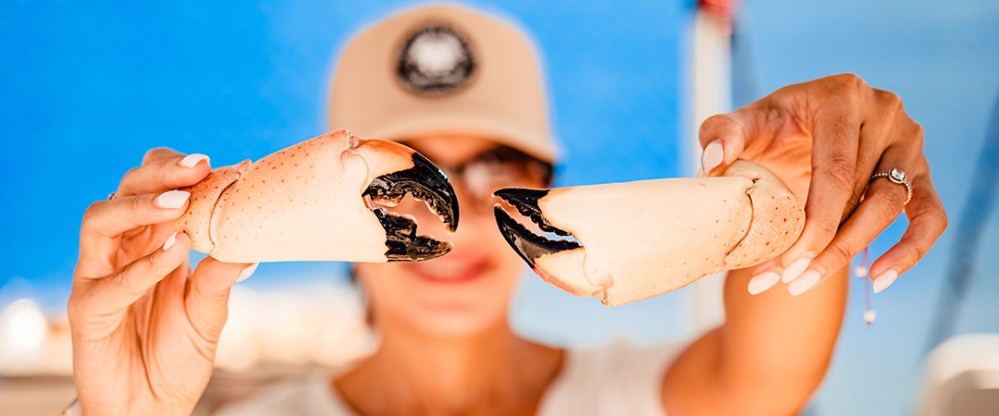 Person holding two large crab claws against a blue background.