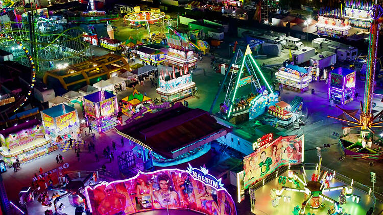 Vibrant night carnival with illuminated rides, games, and booths.