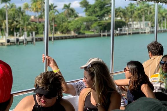 People on a boat looking at water and palm trees on a sunny day.