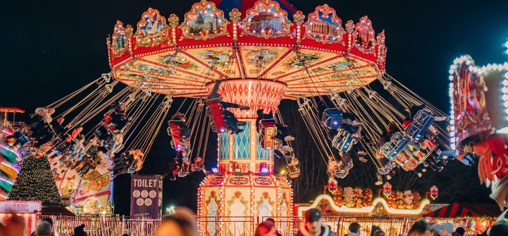 Nighttime carnival ride with people on a colorful spinning swing carousel.