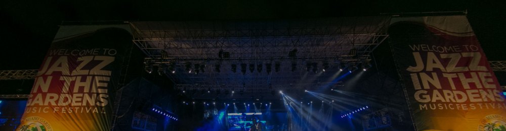 Stage with 'Jazz in the Gardens Music Festival' banners and colorful lights.