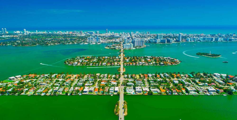 Aerial view of Miami Beach islands connected by roads, surrounded by green water.