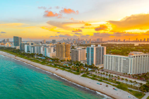 Aerial view of Miami Beach's coastline with high-rise buildings and a vibrant sunset.