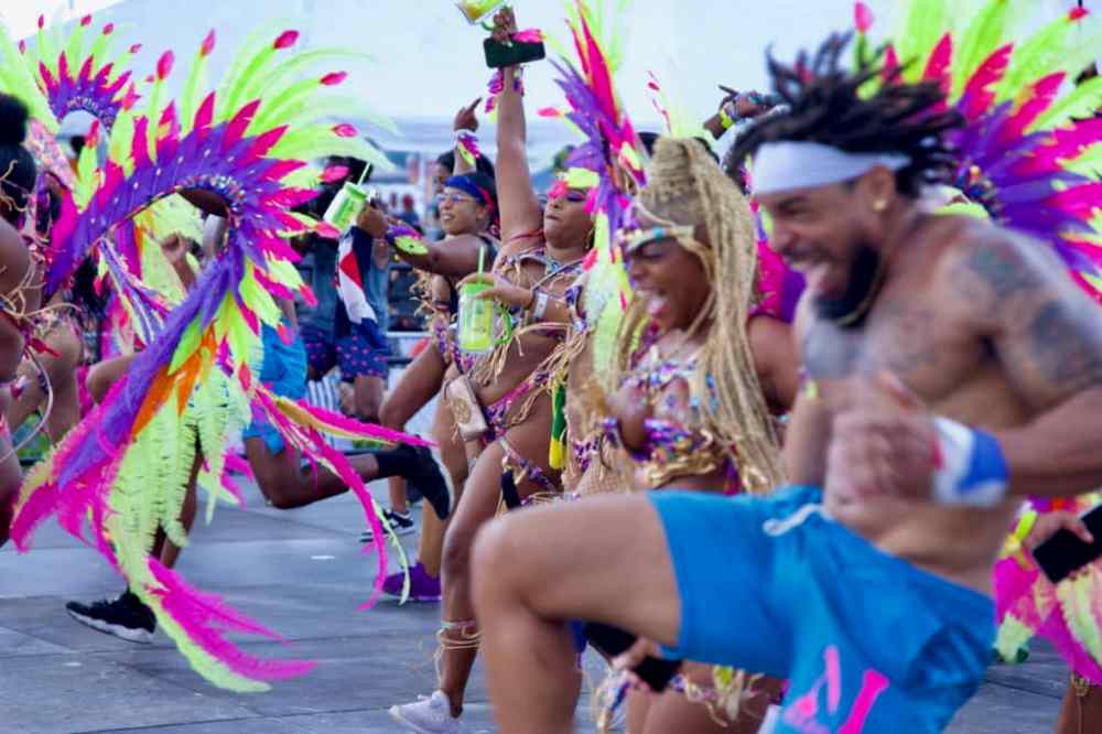 Colorful dancers in vibrant costumes performing energetically at a festival with feathers and accessories.