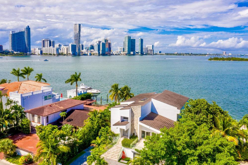 Aerial view of waterfront homes and city skyline with water in between on a clear day.