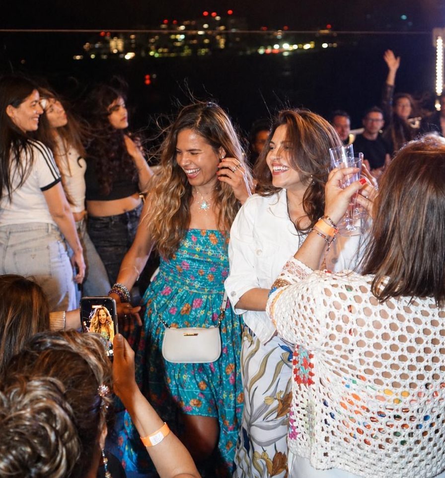 People dancing and smiling at a nighttime outdoor party.