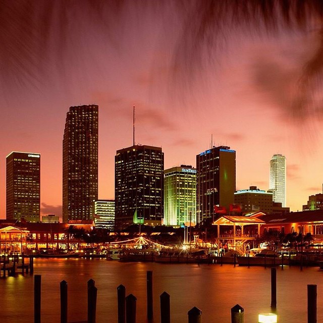 City skyline at dusk with illuminated skyscrapers and waterfront.