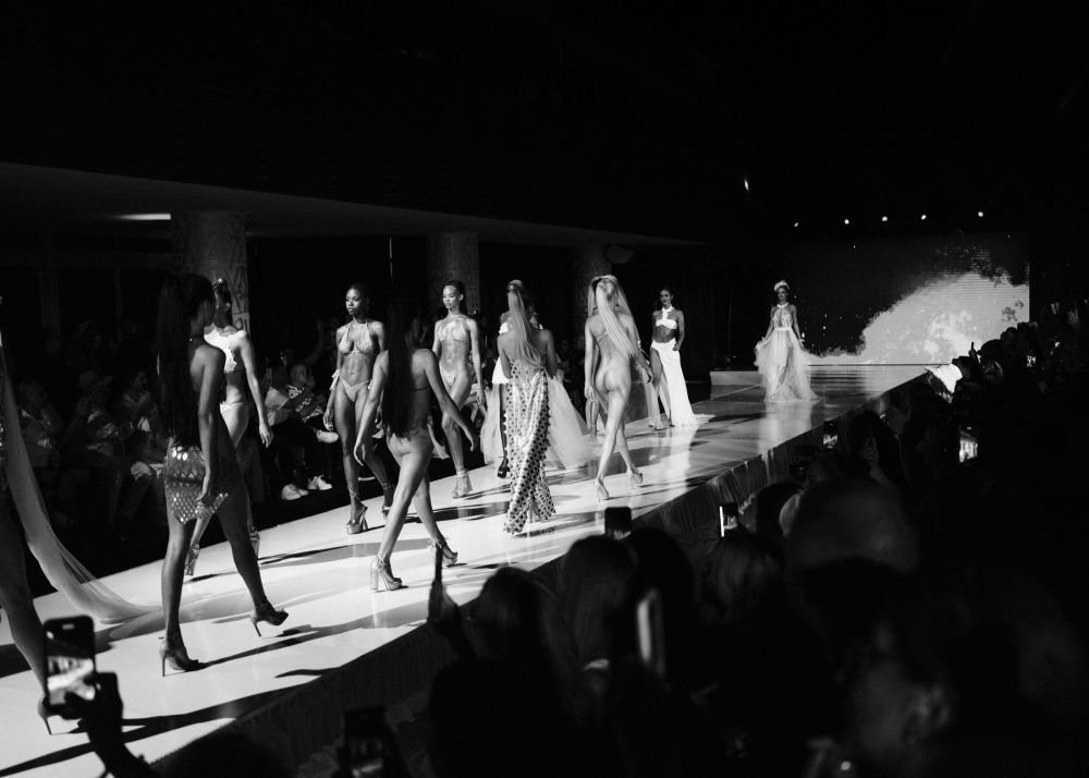 Fashion models walking on runway in a black and white photo.