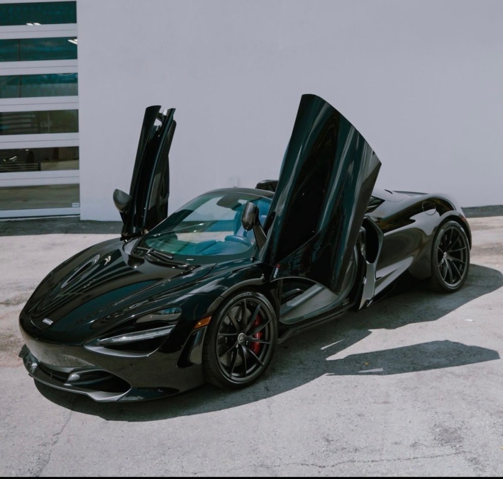 Black sports car with butterfly doors open, angled view.